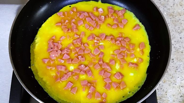 鸡蛋新吃法-双色蛋卷,平底锅加热倒入一层薄薄的油，倒入蛋黄液，晃动平底锅，让蛋液摊匀，小火慢煎
