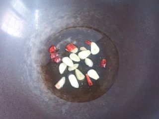 雪菜炒毛豆,锅中倒入适量油烧热，放入蒜片、辣椒炒出香味。
