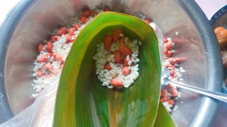 花生蜜枣粽,在漏斗中舀入1/3的花生糯米，拿筷子捅实；