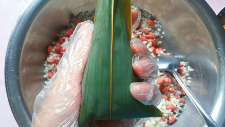 花生蜜枣粽,再把粽叶上端的叶子向下折，直到完全盖住开口的地方就好了；