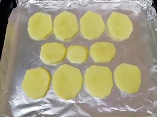 土豆烤鸡翅,烤盘里铺上锡纸，刷上一层食用油，摆上切好的土豆片，烤箱上下管200度预热。