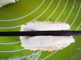 油渣花卷,用筷子按压(如图)，筷子两边会上翘形成花形，然后用双手捏住两端向下折回即成花卷