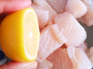 番茄沙司巴沙鱼排,取半个柠檬挤汁在鱼上后用手抓匀并腌制片刻