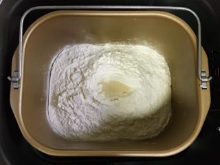 全麦南瓜牛角包,除黄油以外的面包材料都放入面包机内（先液体后粉类的顺序，糖和盐对角放），在面粉中间挖个洞，把酵母粉倒入，启动和面程序。