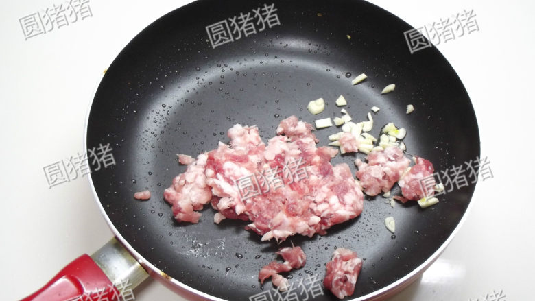 榄菜肉末炒豆角,锅内放入蒜头碎及猪绞肉，用小火煸炒至出油脂。