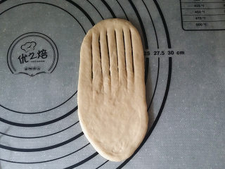 香葱火腿面包卷,取一面团擀成舌形、用刮板在上半部分，均匀地划开几道口子，如图