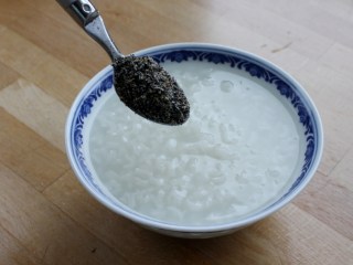 核桃仁芝麻糯米粥,将煮好的粥盛入各自的碗中散上芝麻粉和糖。
