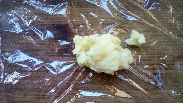 土豆泥玉米球——瘦身减脂,案板上铺上一层保鲜膜，取一勺玉米土豆泥放在上面。