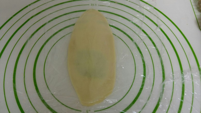 苏式椒盐月饼,盖上保鲜膜，用擀面杖从中间往上干，再从中间往下擀，擀成牛舌状。