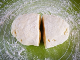 奶香银丝卷,面醒好，揉面垫上撒上少许干面粉，将面团分成两份