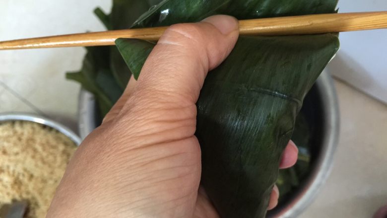 香香肉粽,再加入一勺糯米，将两边叶子向里收拢，上边叶面向下压下盖住不漏米粒