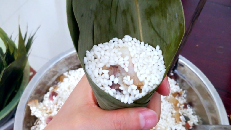 不同类型粽子的包法,把米加到平口就行了，用手稍微压一压。