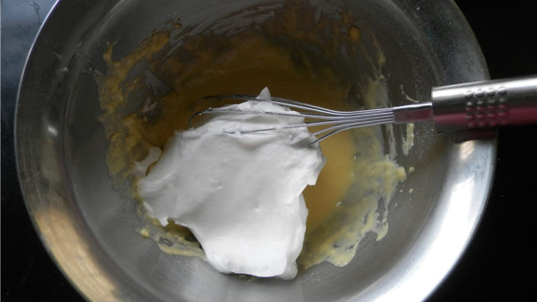 kitty酸奶蛋糕,取三分之一蛋白倒入蛋黄糊中翻拌均匀。