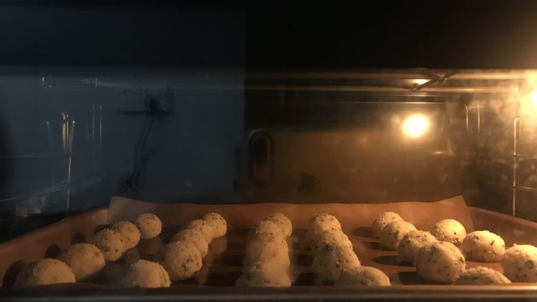  椰蓉芝麻酥球（玉米油板）,送进提前预热好的烤箱中层上下火180度25分钟。