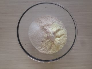 黑芝麻褐麦馒头,将面粉、奶粉和糖倒入盆里，可以看到褐麦粉没有一般的面粉白，用筷子搅拌均匀。