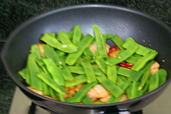 五花肉小酱炖扁豆,倒进扁豆和辣椒，撒点清水，翻炒均匀后遮上锅盖