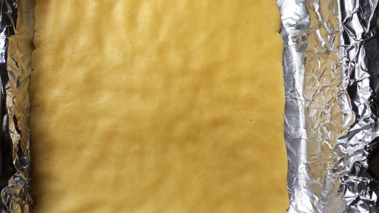 南瓜子酥,面团放在烤盘上，用手压成约1cm厚的方形面团，入预热好的烤箱，170度，15分钟左右，直到微微发黄