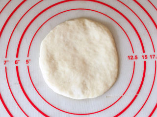 日式红豆包,取一份松弛好的面团压扁，用擀面杖擀成圆形面皮。