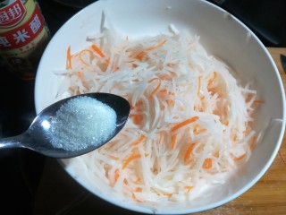 凉拌白萝卜丝,腌好的萝卜放入两勺糖，用手抓拌均匀，加了一些糖后，萝卜吃起来口感不会那么辣。