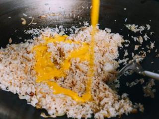 虾仁炒饭,鸡蛋打好,把蛋液加入锅里，快速混合搅拌，这样蛋液可以沾到每一粒米饭。