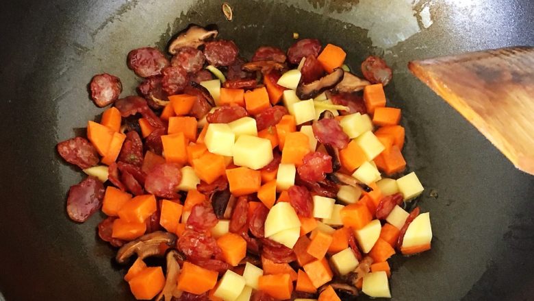 腊肠土豆焖饭,等腊肠微微出油变透明后加入胡萝卜和土豆丁，继续翻炒，直到胡萝卜土豆断生。加入少许盐和老抽调味