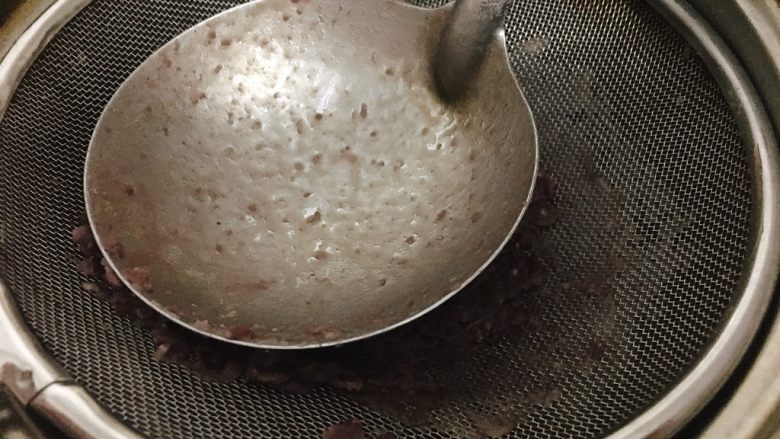 桃胶陈皮红豆沙,舀出红豆到筛子上，用大汤勺背推压红豆。