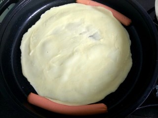 快手鸡蛋煎饼,火腿肠去皮切成两半，放到锅中，煎一会儿，待饼成形，火腿翻面