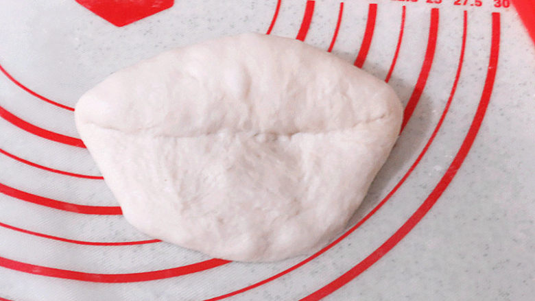 美味时尚面包【纺锤形砂糖黄油餐包】,使面团光滑的一面朝下，将面团较远端向中间折入三分之一