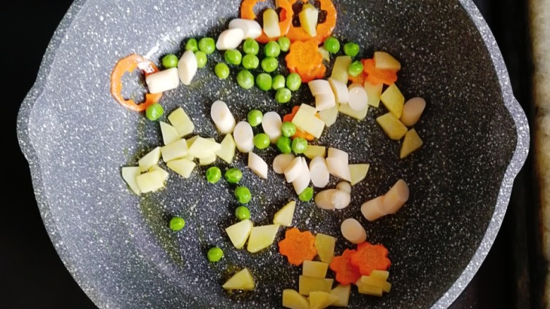 宝宝辅食—土豆鳕鱼肠炒意面,倒入煮熟的豌豆和鳕鱼肠翻炒均匀