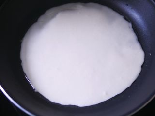 蔬菜可丽饼,舀一半面糊倒入锅中，晃动煎锅使面糊流淌均匀。剩下的面糊可以再做一份。