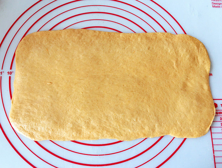 全麦南瓜面包,取一个松弛好的面团，用擀面杖擀成15*28cm的长方形面片，尽量中间厚，两边薄一些。