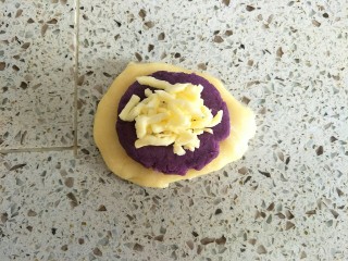 紫薯仙豆糕,取一个面皮压扁，包入紫薯馅和马苏里拉芝士，虎口收口
