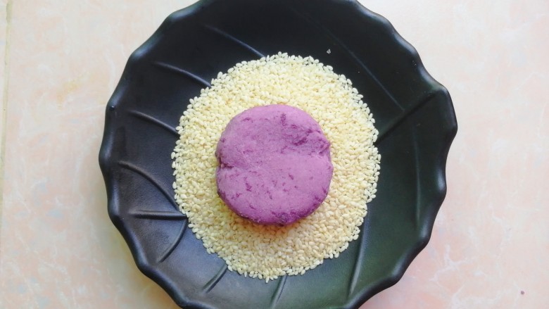 紫薯芝麻饼,取一小份静置好的面团，揉圆按扁，沾少许芝麻