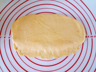 全麦奶香南瓜排包,松弛好的面团擀成椭圆形，上厚下薄，以便于粘合。