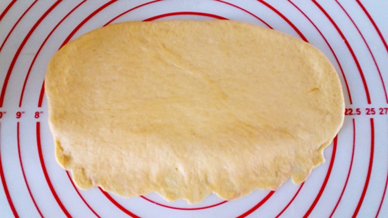 全麦奶香南瓜排包,松弛好的面团擀成椭圆形，上厚下薄，以便于粘合。