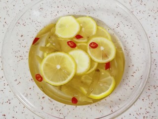 泡椒柠檬花生鸡爪,玻璃盆里面放入泡椒和泡椒水，加入纯净水、糖、白醋、盐、柠檬片和小米椒，搅拌至糖和盐融化。