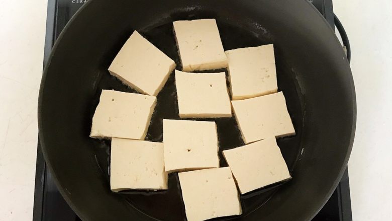 油豆腐烧肉,炒锅刷一层大豆色拉油，烧热后加入豆腐片，温火煎制，煎至一面金黄就翻面