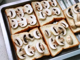 快手营养早餐11,把圆菇片摆在面包片上，喜欢吃番茄酱的朋友可以在面包片上抹一层，再放蘑菇；