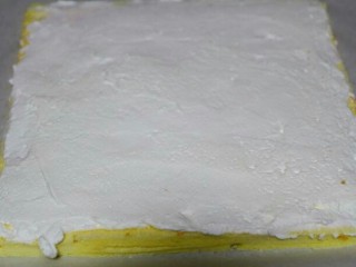 芒果蛋糕卷,将准备好的淡奶油和白砂糖倒入打蛋盆中，用打蛋器打发至出现清晰的纹路不消失的状态。将打发好的淡奶油倒在蛋糕表面用刮刀均匀地抹匀
