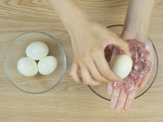 干脆面版苏格兰蛋,取适量拌好的猪肉末在掌心铺平，放上水煮蛋