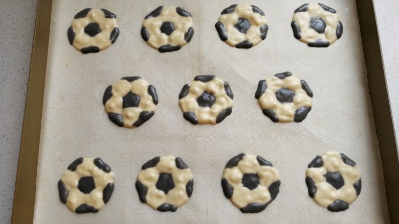 足球慕斯蛋糕卷,然后把先前画好的足球图形垫在油布或油纸下，再用先前装入裱花袋中的两种蛋糊画出足球图形，画好后把A4稿纸抽出即可。