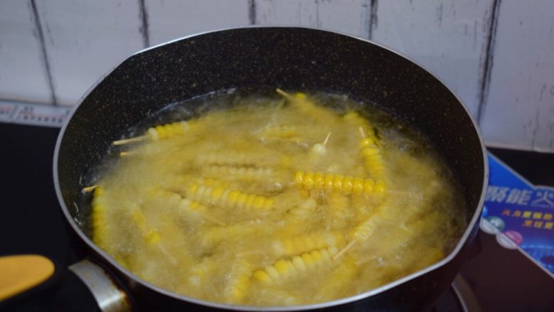 孜然玉米串,锅中倒入适量的食用油烧热，放入玉米串大火炸5秒