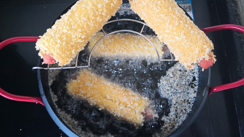 【芝士烤肠吐司卷】,锅中倒油大火烧开，放入吐司卷开始炸，炸至金黄。放在晾网上滤油。