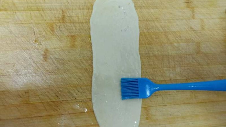 甜味盘丝饼,取一个面条，擀面杖上均匀抹油，擀成长条形，用刷子均匀抹油。