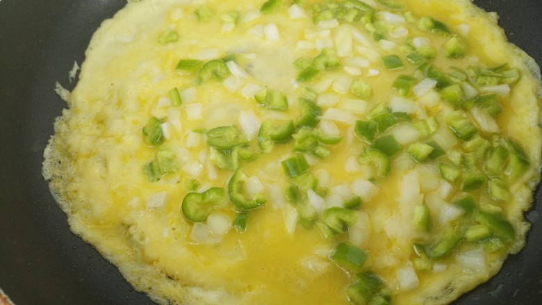 青椒洋葱鸡蛋饼,然后把鸡蛋液倒入锅内。开小火摊鸡蛋饼。