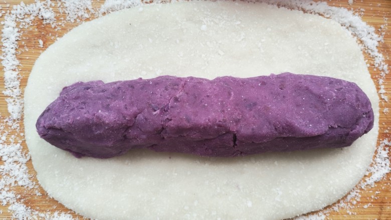 紫薯糯米糍,用擀面杖将糯米粉团擀成长方形糯米饼后将事先捏好的紫薯条放在上面