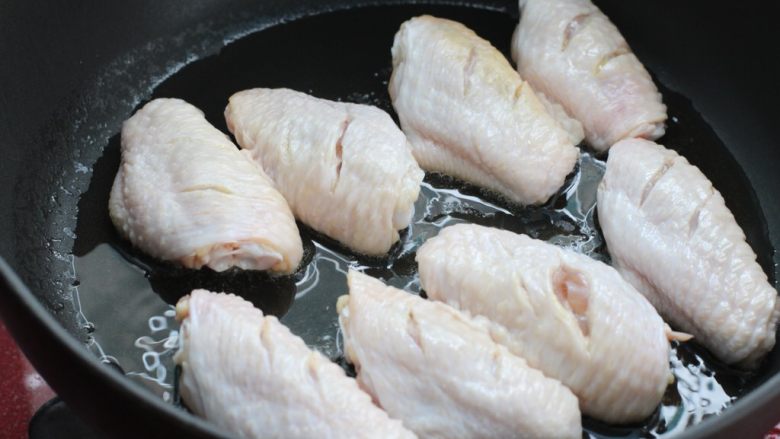 红烧鸡翅炖土豆,锅中倒适量食用油烧热，鸡翅中用厨房纸擦干多余水分放入锅中
