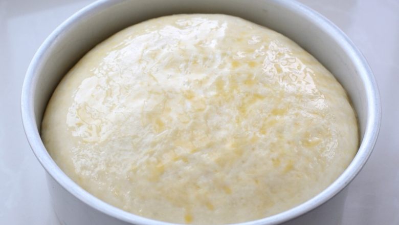 奶酪面包,再次将面团发酵至模具的八分满，可以放进烤箱里，下面放一碗热水来帮助发酵，在发酵好的面团表面刷一层薄蛋液