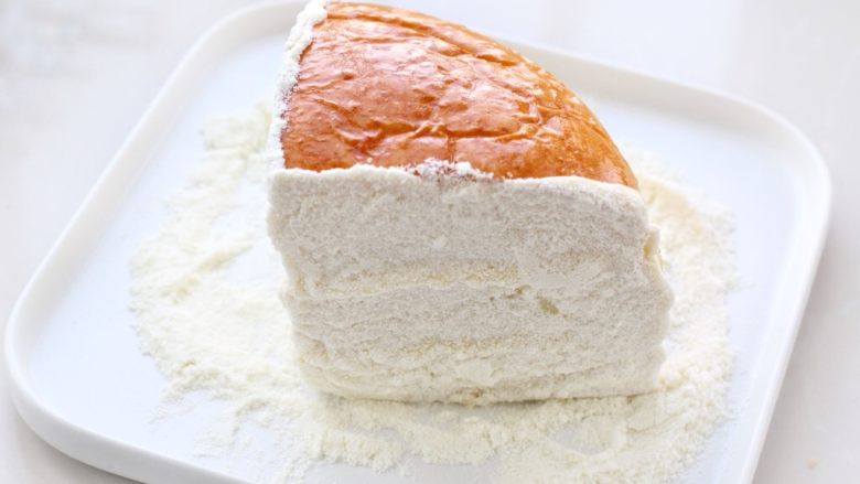 奶酪面包,把有奶酪馅的切面放到奶粉中，粘上厚厚的一层奶粉，奶酪面包就做好了