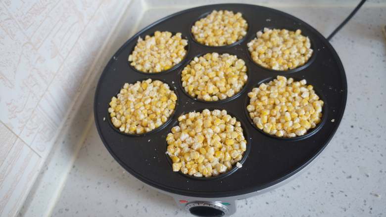 冰花玉米烙,煎饼机刷一层食用油，放入适量玉米粒，稍微压平